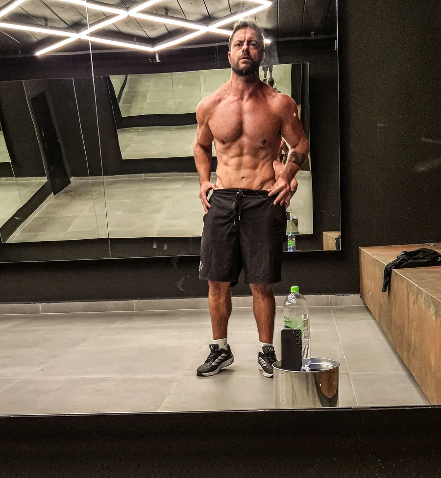Montinho Personal de frente ao espelho da academia, mostrando a definição do abdômen — treinador que atende os condomínios de Tamboré e Alphaville